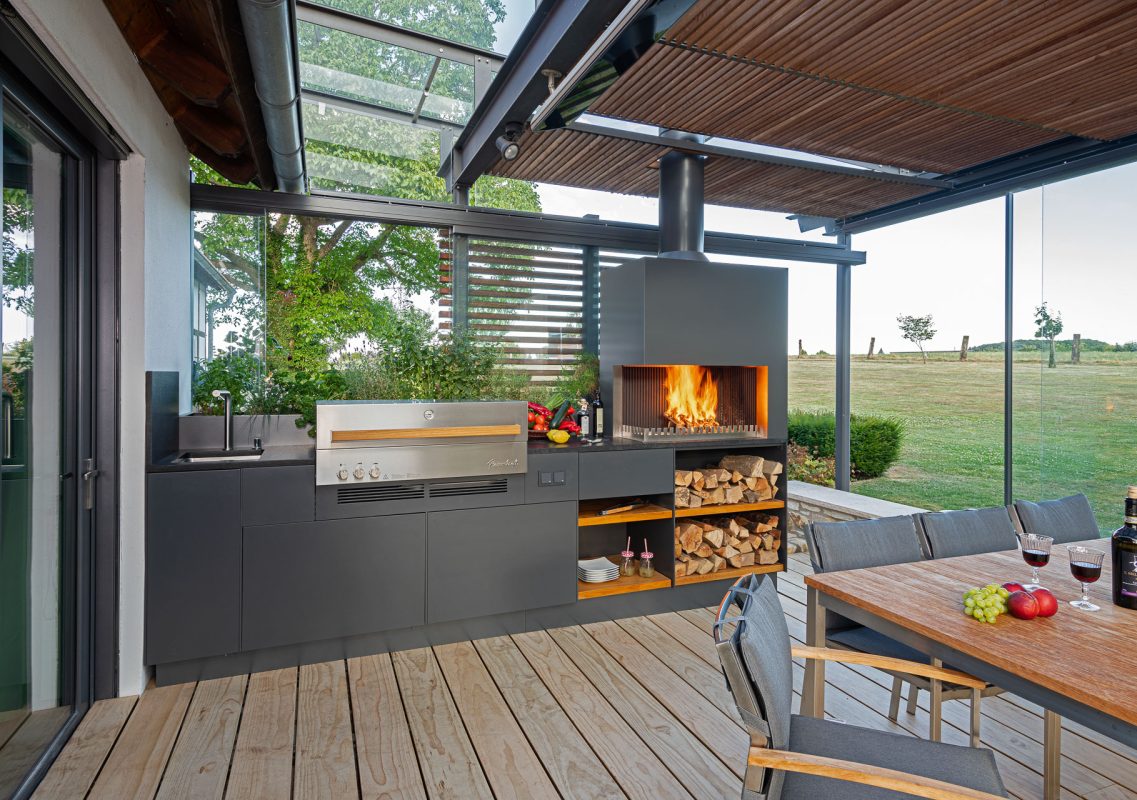 Überdachte Terrasse mit Outdoorküche, Grill-Feuerstelle und Esstisch am Feld