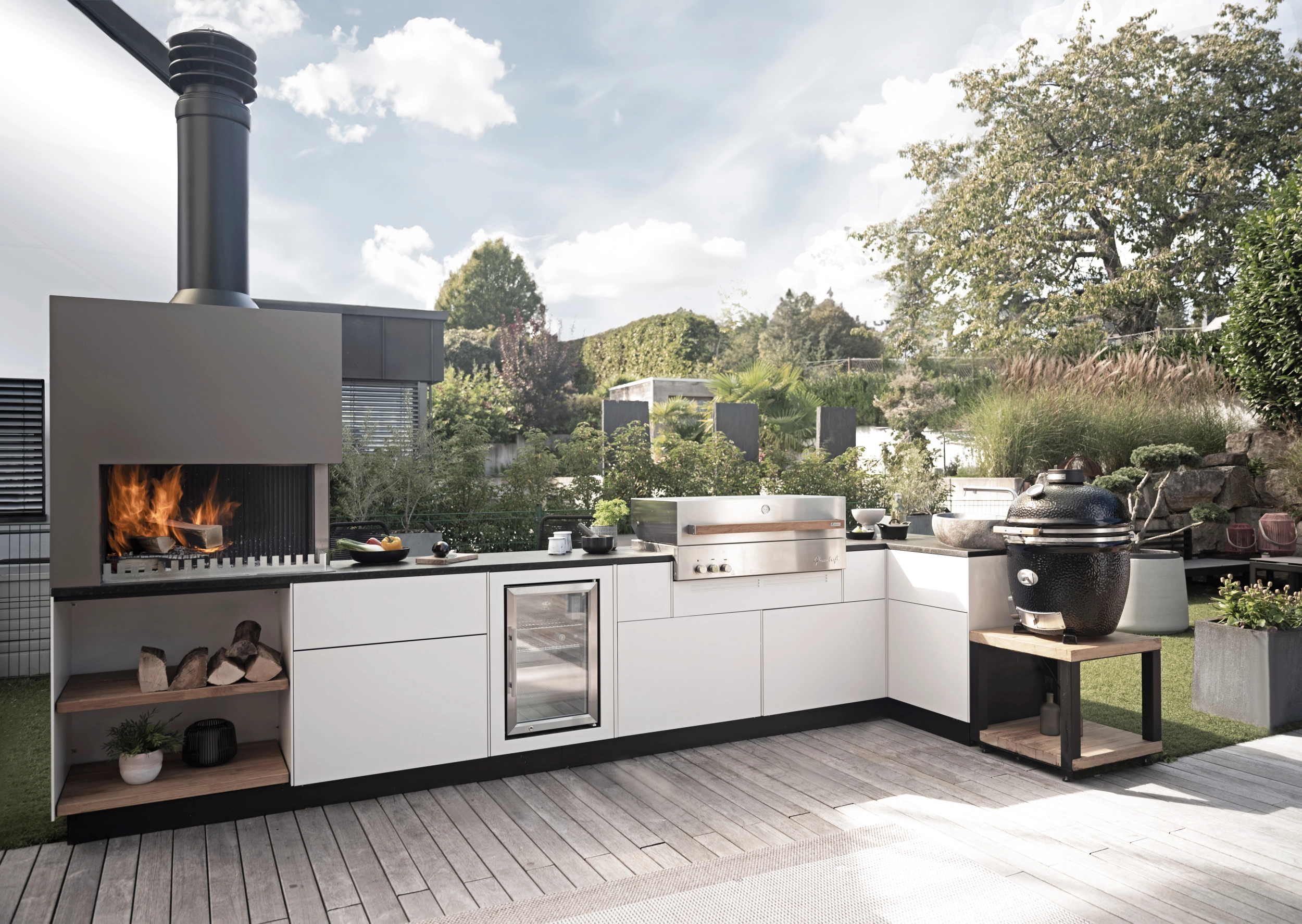Eine Outdoorküche mit Feuerecke, Kühlschrank, Grill und Wasseranschluss
