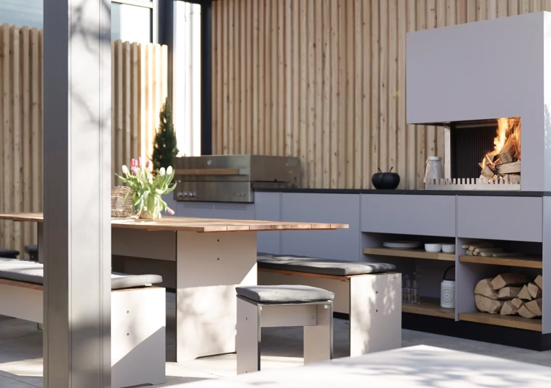 Überdachte Outdoorküche mit Feuerstelle und Sitzbank im Showroom-Außenbereich