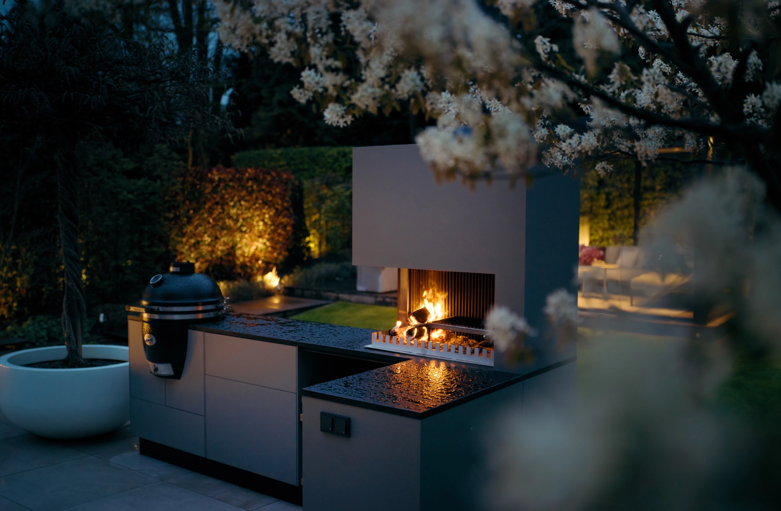 FREILUFT Outdoorküche mit Grill-Feuerstelle und Kamado am Abend, Gartenbeleuchtung im Münsterland