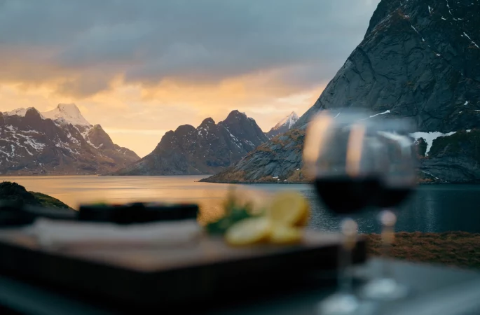Rotweinglas auf der Arbeitsplatte vor der Fjordlandschaft in Norwegen