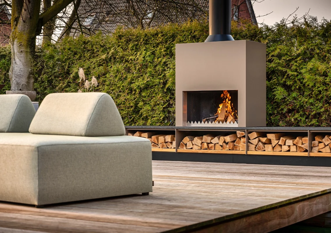 FREILUFT Feuer mit Holzlager neben heller Loungeecke auf dem Deck